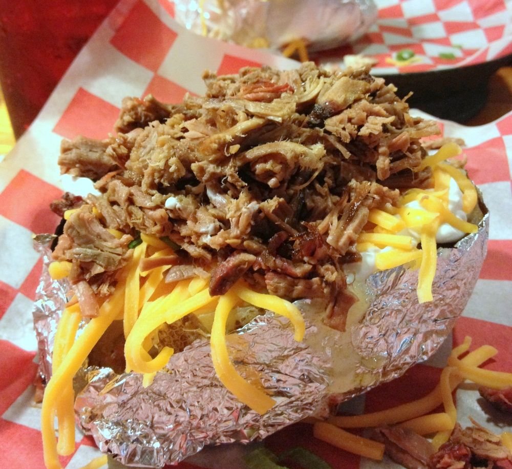 Baked potato in foil loaded with chopped brisket and shredded cheese