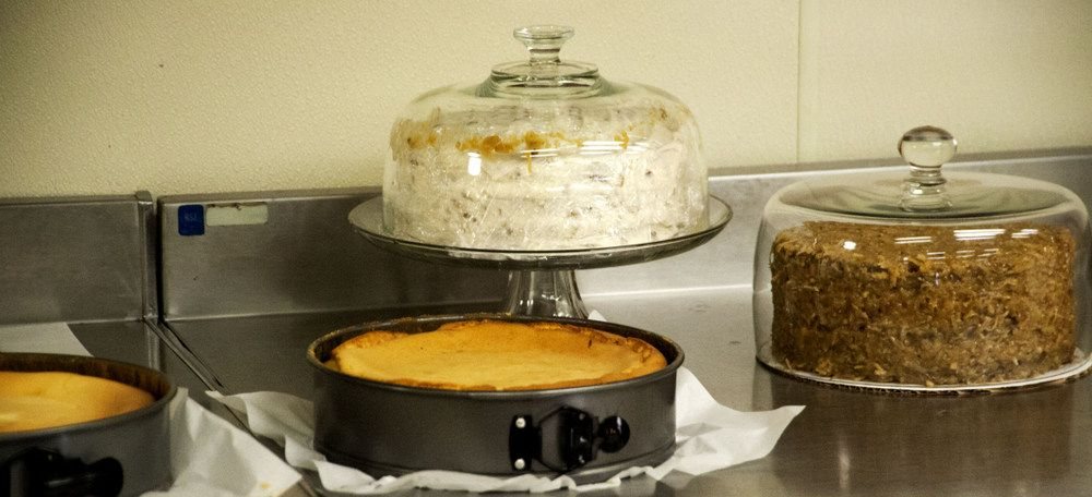 Whole cakes and cheesecakes under glass domes on the bakery counter